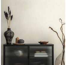 Dekoratives Interieur mit schwarzem Schrank, Vasen und Trockenblumen auf beiger Tapete.