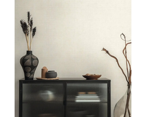 Dekoratives Interieur mit schwarzem Schrank, Vasen und Trockenblumen auf beiger Tapete.