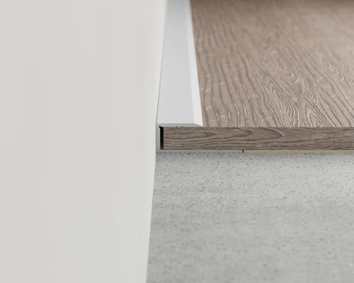 Detailansicht einer Fußleiste an einer Wand und einem Bodenbelag.