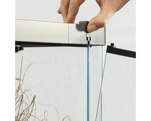 Detailansicht eines Aquariums mit Glasabdeckung und einer Hand, die die Abdeckung anbringt