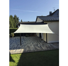Rechteckiges Sonnensegel über einer Terrasse mit Pflastersteinen und Rasenfläche.