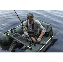 Mann angelt in einem grünen aufblasbaren Boot auf dem Wasser