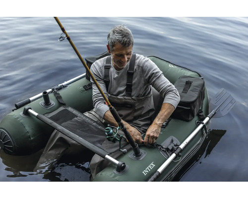 Mann angelt in einem grünen aufblasbaren Boot auf dem Wasser