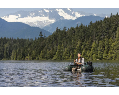Mann angelt vom Schlauchboot auf einem See mit Bergpanorama.