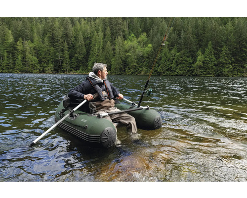 Mann in einem Intex Schlauchboot mit Ruder und Angel im See