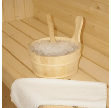 Holzeimer mit Eis und Schöpfkelle in einer Sauna, neben einem Handtuch.