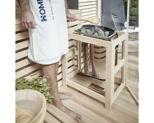 Sauna-Szene mit Person, Handtuch, Holzkelle, Steinen und Saunaofen