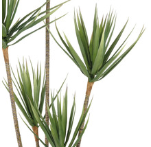 Künstliche Grünpflanze mit langen, spitzen Blättern an braunen Stängeln.