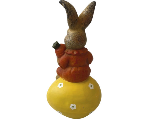 Dekorativer Hase auf einem Osterei mit Karotte in der Hand als Gartendekoration
