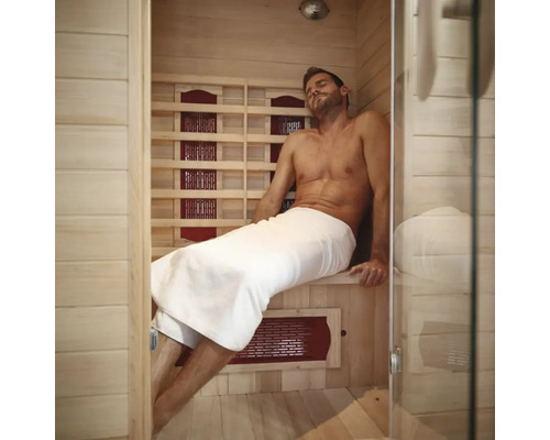 Mann entspannt in einer Infrarotsauna mit Holzwänden und Glasfront