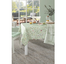 Gedeckter Tisch mit Tischdecke mit Blumenmuster und Stühlen in einem hellen Raum.