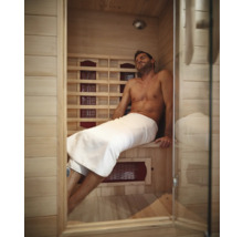 Mann entspannt in einer Infrarotsauna mit Holzwänden und Glastür
