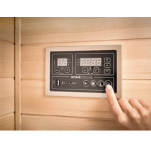 Nahaufnahme eines Bedienfelds in einer Sauna mit einer Hand, die den Ein- und Ausschaltknopf drückt