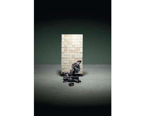 Kapp- und Gehrungssäge mit Akku vor Wand aus quadratischen Elementen