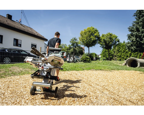 Metabo Logo. Eine Kapp- und Gehrungssäge steht im Freien auf einem Untergestell.
