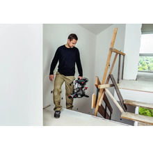 Ein Mann trägt eine Kappsäge auf einer Baustelle.