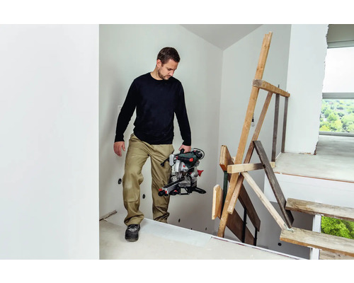 Ein Mann trägt eine Kappsäge auf einer Baustelle.