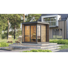 Helle moderne Außensauna mit Holzfassade und Glaswänden auf einer Terrasse neben einem Pool und Liegestühlen vor einem modernen Haus im Wald.