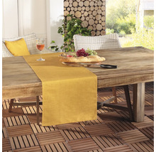 Szene mit einem Esstisch im Freien mit Tischläufer, Brot, Weintrauben und einem Glas Wein.