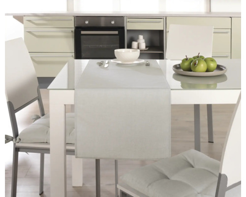 Esstisch mit Tischläufer, Geschirr und Stühlen in einer Küche.