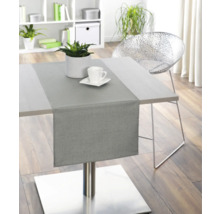 Esstisch mit Tischläufer, Pflanze und Geschirr in einem hellen Raum