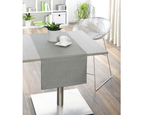 Esstisch mit Tischläufer, Pflanze und Geschirr in einem hellen Raum