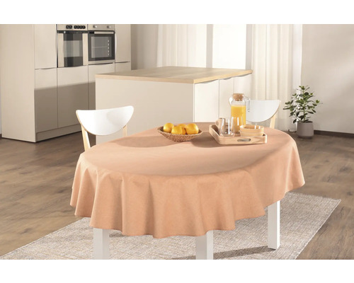 Gedeckter Esstisch mit Tischdecke, Saft, Obst und Geschirr in einer hellen Küche.