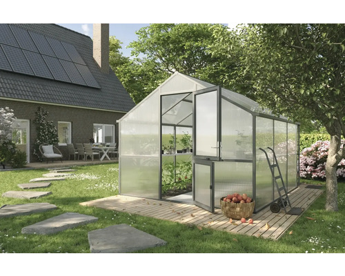 Gewächshaus im Garten mit geöffneter Tür, Schubkarre und einem Korb voller Äpfel.