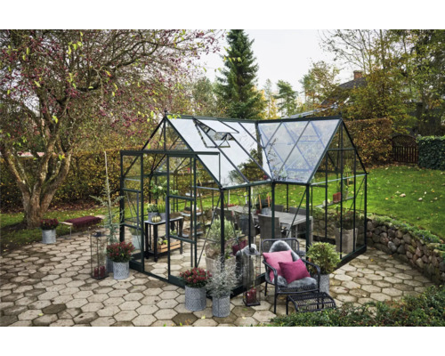 Gewächshaus mit Pflanzen und Möbeln im Garten.