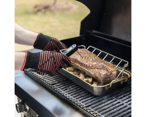 Eine Person misst die Temperatur eines Fleischstücks auf einem Grill mit einem digitalen Thermometer und Hitzeschutzhandschuhen.