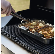 Grill mit Garnele, Mais und Gemüse in einer Edelstahlpfanne, eine Hand benutzt eine Zange.