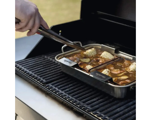 Grill mit Garnele, Mais und Gemüse in einer Edelstahlpfanne, eine Hand benutzt eine Zange.