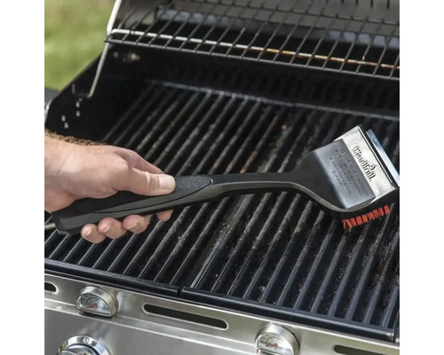 Eine Hand benutzt eine Grillbürste zur Reinigung eines Grills.