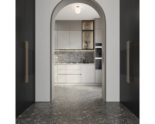 Blick durch einen Bogen auf eine moderne Küche mit grauer Arbeitsplatte und Fliesenboden