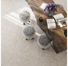 Heller Boden mit Terrazzo-Optik, Holztisch und drei Hockern mit Fellbezug