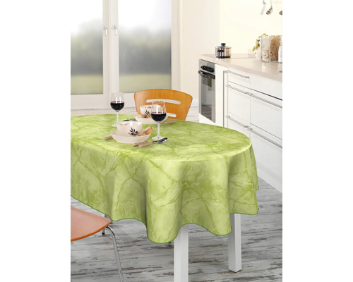 Esstisch mit hellgrüner Wachstuchdecke und Geschirr in einer hellen Küche.