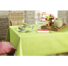 Gedeckter Esstisch mit grüner Tischdecke, Geschirr, Karaffe, Blumen und Buch