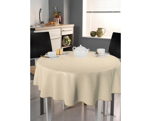 Beigefarbene Tischdecke auf einem runden Tisch in einer Küche mit Geschirr