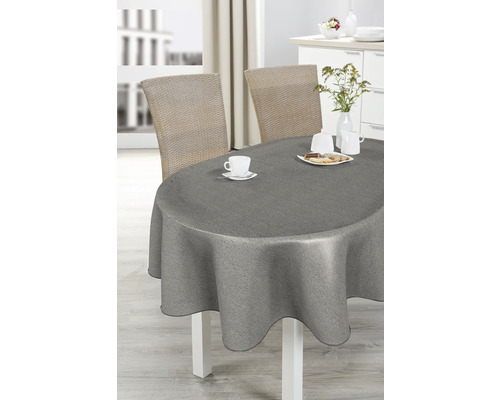 Esstisch mit grauer Tischdecke, Geschirr und Rattanstühlen in hellem Raum.