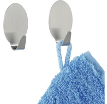 Zwei selbstklebende Haken aus Metall, einer mit einem Handtuch