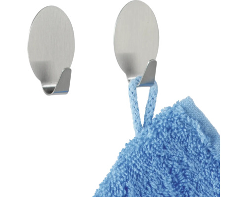 Zwei selbstklebende Haken aus Metall, einer mit einem Handtuch