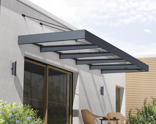Modernes Vordach aus Aluminium und Glas über einer Terrassentür an einer Hauswand.