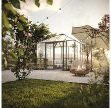 Gartenszene mit Gewächshaus, Sitzbereich, Sonnenschirm und Feuerstelle