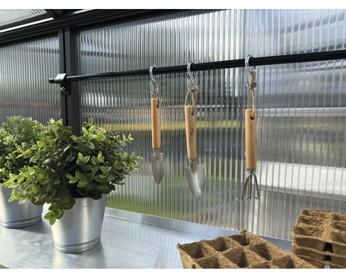 Innenansicht Gewächshaus mit Gartenwerkzeug, Anzuchttöpfen und Pflanzen