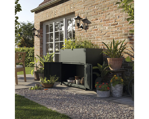 Szene im Freien mit Pflanzkasten, Schrank und verschiedenen Topfpflanzen vor einer Ziegelwand