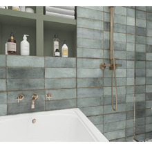 Badezimmer mit rechteckigen Wandfliesen, Badewanne und Duscharmatur.