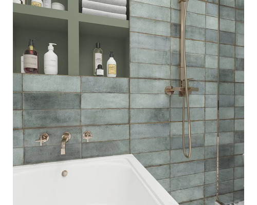 Badezimmer mit rechteckigen Wandfliesen, Badewanne und Duscharmatur.