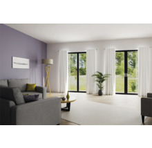 Helles Wohnzimmer mit Sofa, Stehlampe und großen Fenstern mit Vorhängen