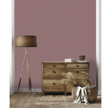 Zimmeransicht mit geriffelter Tapete, Kommode, Lampe und Teppich