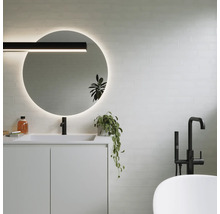 Modernes Badezimmer mit rundem Spiegel, Waschtisch, Armatur und Badewanne.